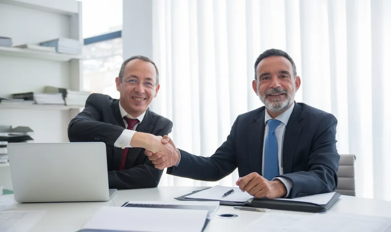 Two business owners shaking hands after agreeing a company sale