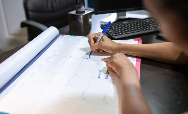 Woman planning her schedule on a desk calendar in an office