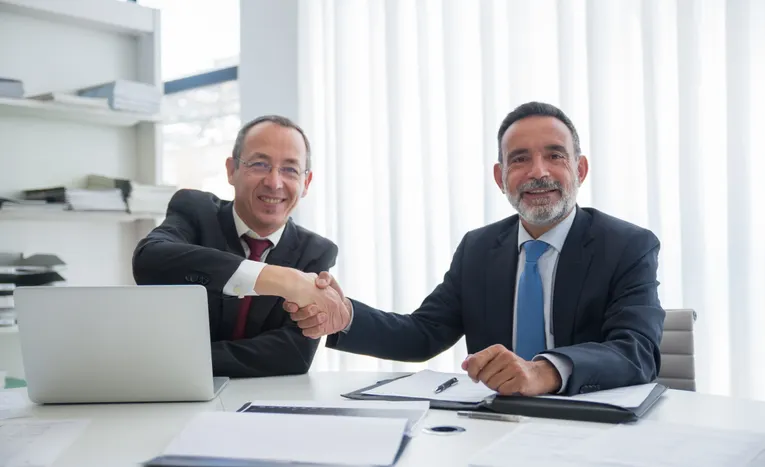 Two business owners shaking hands after agreeing a business sale