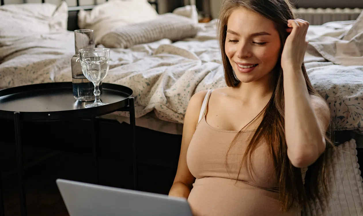 Pregnant employee working on a laptop before maternity leave