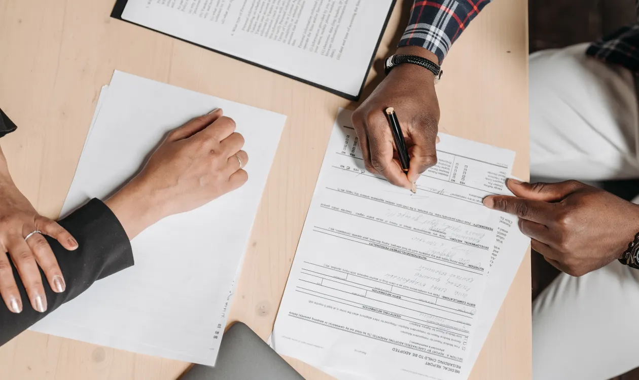 Two people reviewing and signing a UK business invoice at a desk